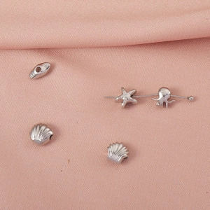 Macro shot of silver ocean charms featuring starfish and octopus on pink silk