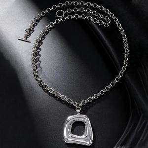 Gros plan d'un collier à grosse chaîne argentée avec un pendentif géométrique creux