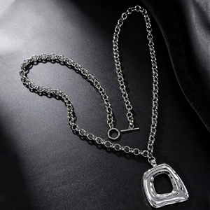 Vue détaillée d'un collier à grosse chaîne argentée avec un pendentif géométrique