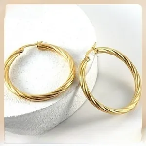 Detailed macro shot of vintage golden twisted hoop earrings on a marble stone pedestal