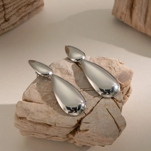Detailed close-up of silver teardrop earrings with polished metallic mirror finish