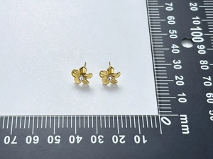 Macro shot of gold flower earring with crystal center, showing 10mm size on a ruler