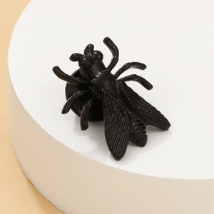 Gothic style black fly insect brooch with detailed wings on a minimalist round white stand