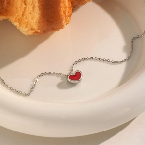 Elegante französisch-romantische Silberhalskette mit rotem Herzanhänger auf Teller