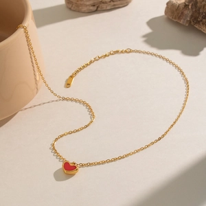 Detaillierte Ansicht einer goldenen Kette mit einem winzigen roten Herzanhänger