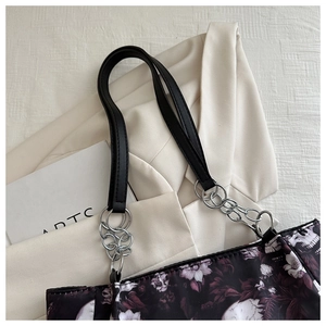 Detail of gothic floral tote bag with skull print and metallic chain shoulder strap