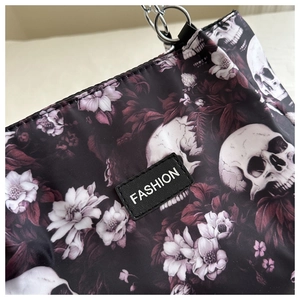 Detail of floral skull print tote bag with metal chain strap and fashion label