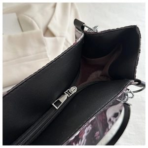 Macro view showing the smooth metal zipper and black interior compartment of the skull tote bag