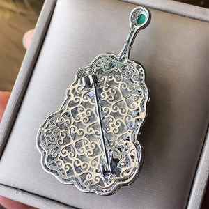 Gourd-shaped brooch back view featuring hollow patterns and emerald green gemstone