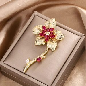 Elegant gold flower brooch with red marquise gems and white zircons on silk fabric