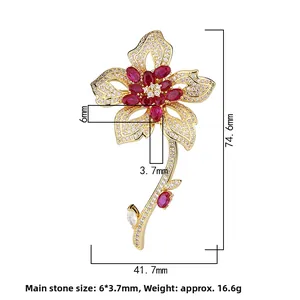 Detailed view of luxury gold floral brooch with red gems and white zircon inlay