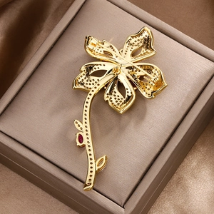 Golden flower brooch back view with honeycomb setting and ruby inlay on satin fabric