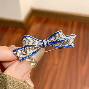Close-up of a blue enamel bow brooch with sparkling crystals and silver finish
