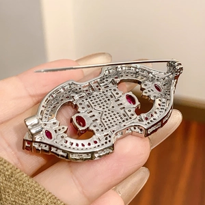 Close-up of vintage style silver brooch back detailing with secure pin clasp and red gemstones