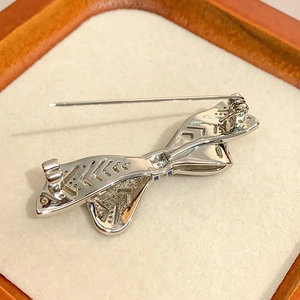 Detail of silver bow brooch back showing intricate geometric hollow patterns and safety pin