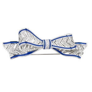 Sparkling silver bow brooch with blue enamel and white crystals on a white background