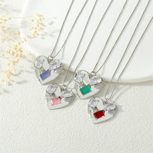 Detail of copper 18K plated heart pendants with colorful zircons on white ceramic