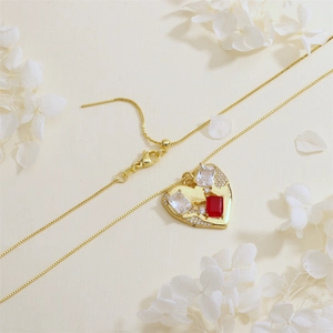 Detail of gold heart pendant with red and white rectangular zircons and tiny diamonds