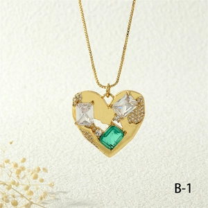 Macro detail of gold heart pendant necklace with green emerald-cut zircon and box chain