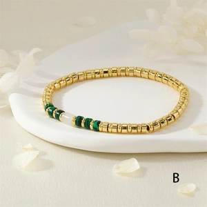 Detail van een boheemse armband met gouden kralen, groene malachiet en witte stenen