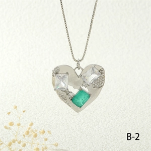 Close-up of heart pendant with emerald gemstone and zircon inlay on silver box chain