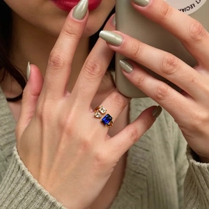 Détail d'une bague ajustable dorée à l'or 18K avec zircon bleu de taille émeraude