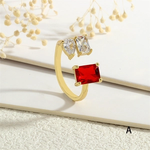 Détail de la bague dorée réglable avec zircon rouge et pierres claires facettées