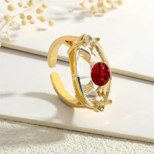 Makroaufnahme von vergoldetem offenem Ring mit Marquise-Kristall und rotem bösem Blick