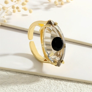 Detailaufnahme eines goldenen Evil-Eye-Rings mit großem Kristall auf weißem Display