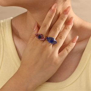 Nahaufnahme der Evil Eye Ringe mit pinkfarbenen und blauen Kristallen auf goldenem Band