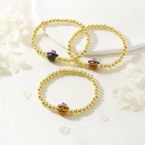 Close-up of three-piece Halloween beaded bracelet set with gold finish and pumpkin charms