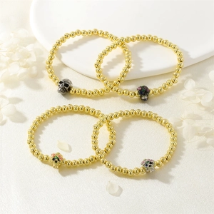 Macro detail of gold-plated beaded Halloween bracelets with gemstone-set skull charms