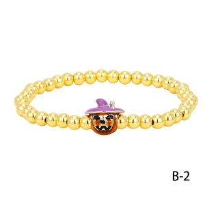 Detailed macro view of a Halloween gold beaded bracelet with a pumpkin witch hat charm