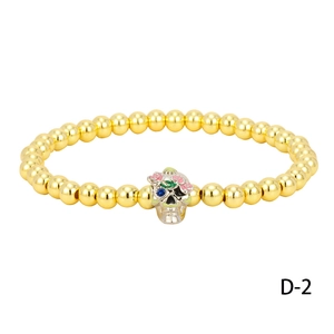 Close-up of golden beaded bracelet with skull charm and colorful crystal accents