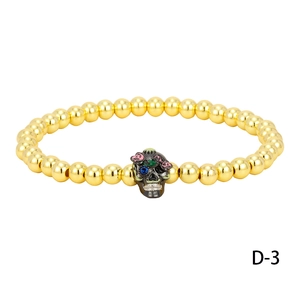 Detail of beaded bracelet with gold copper beads and a skull pendant with blue gem eye