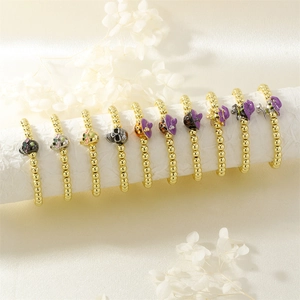 Macro shot of gold bead Halloween skull bracelets with enamel charms on white rolls
