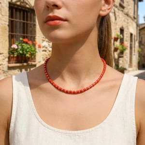 Close-up of handmade red semi-precious stone bead necklace with gold spacers on a model