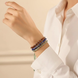 Close-up of three layered beaded barrel bracelets with adjustable green woven cords