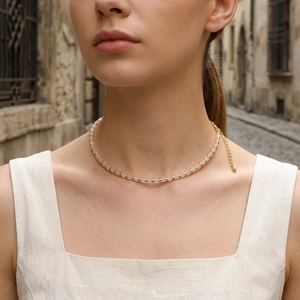 Detail of pink matte beads and gold spacers on a choker necklace worn by a model