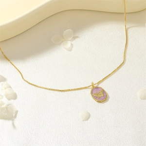 Detailansicht einer Goldkette mit achteckigem Anhänger, lila Emaille und Schmetterling