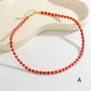 Detail view of red cylindrical beads with golden spacers on a choker necklace band