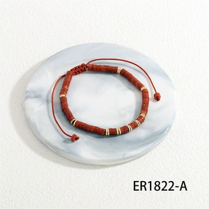 Detailed shot of handmade semi-precious stone bead bracelet with red woven cord and gold spacers