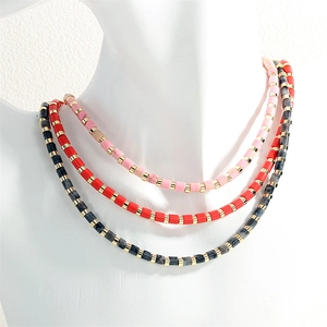 Detail of multi-layered beaded necklace featuring pink, red, and gray stones with gold spacers