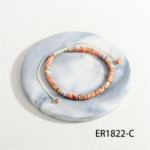 Macro detail of Bohemian woven bracelet with orange marble beads and gold spacers on marble tray