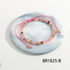 Detail van roze halfedelsteen geweven armband met gouden kralen en verstelbaar koord