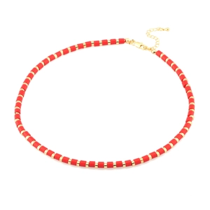 Handmade beaded necklace with red cylindrical beads and gold disc spacers on white background