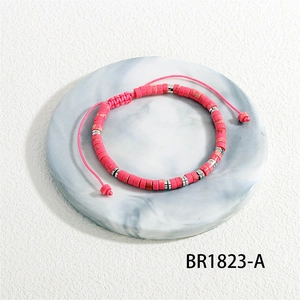 Macro detail of handmade woven bracelet with pink barrel beads and silver spacers on marble
