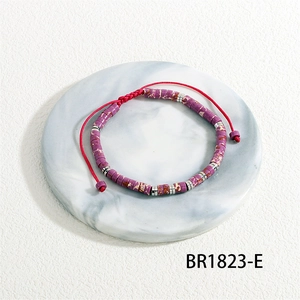 Detail of woven bracelet featuring purple semi-precious tube beads and red cord adjustment