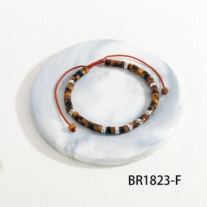 Detail of tiger eye bead bracelet with silver spacers and red adjustable cord on marble tray