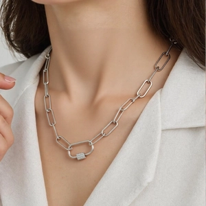 Dettaglio di una collana a catena con moschettone argento hip-hop su una modella con zirconi